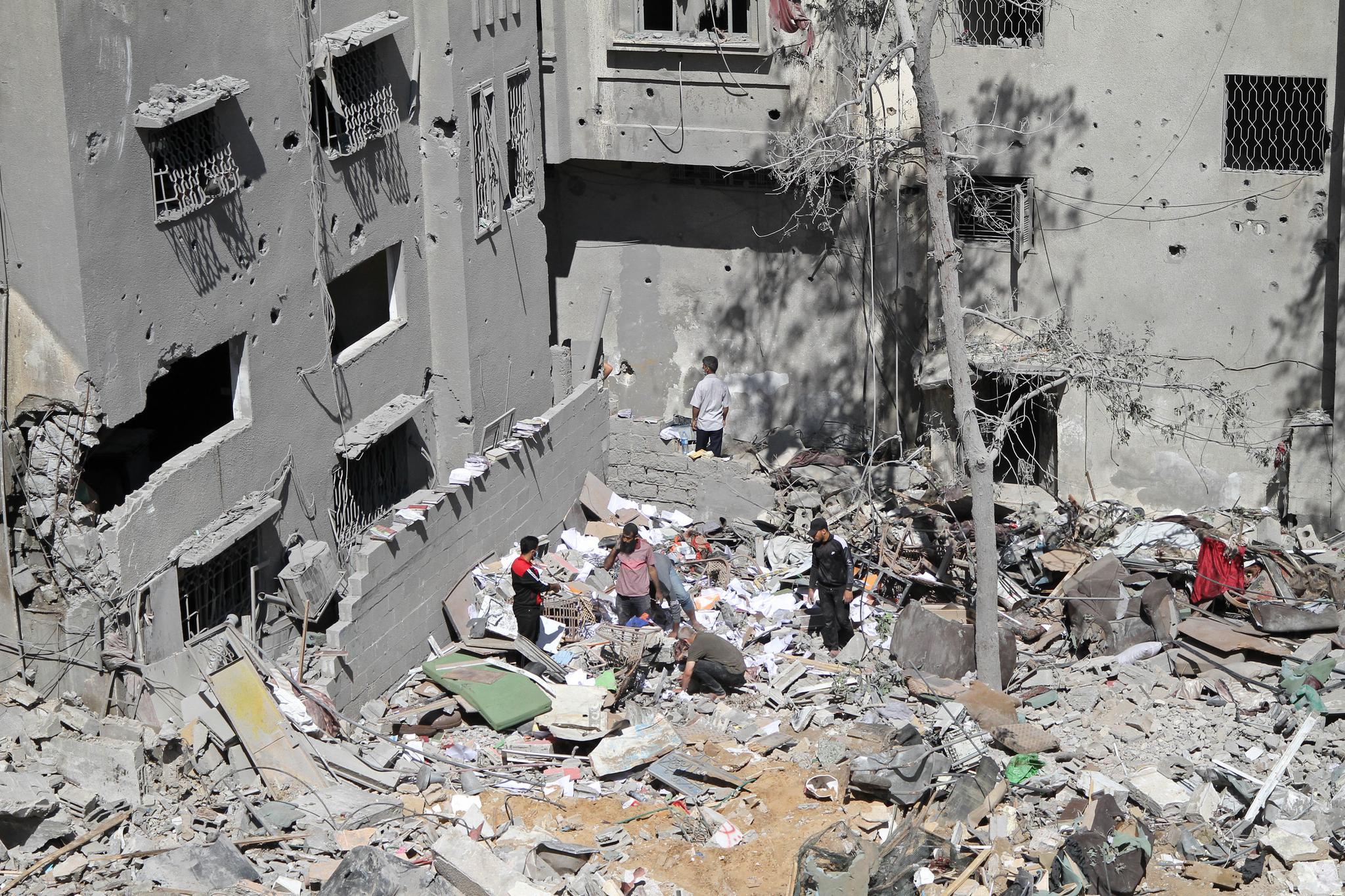 当地时间5月15日，巴勒斯坦人站在空袭过后的位于加沙城西部的沙提难民营废墟间。新华社 图