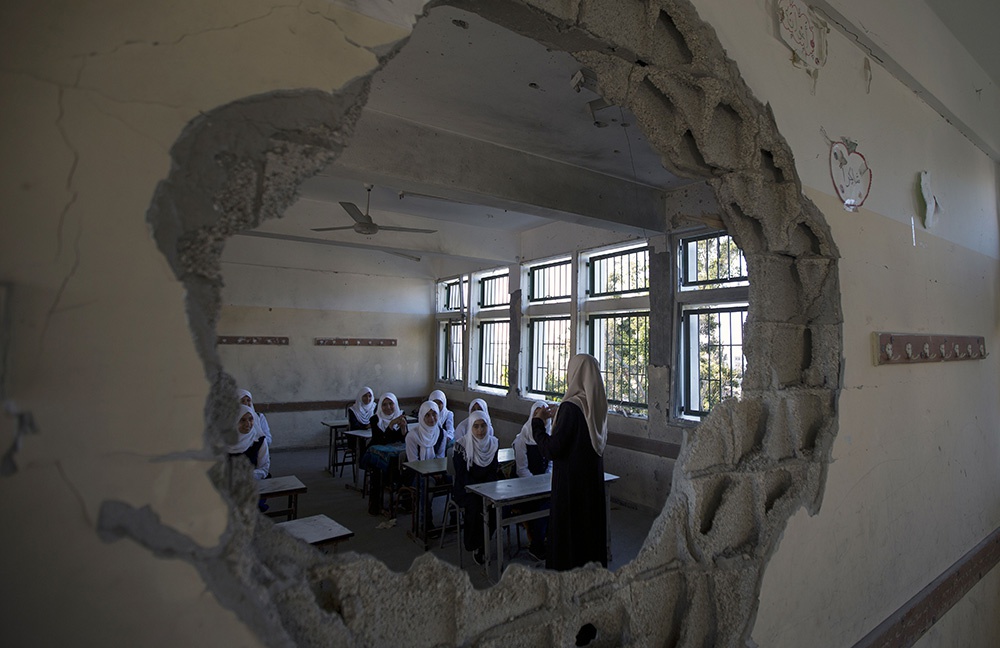 当地时间2014年9月14日，加沙，巴勒斯坦学生迎来开学第一天，他们穿过废墟，在以色列炮击中被破坏的学校上课。人民视觉 资料图