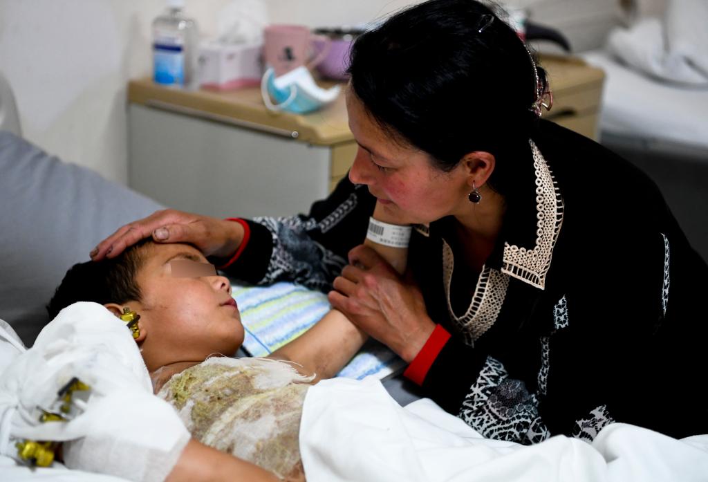 在新疆医科大学附属中医医院，断臂男孩和妈妈苏迪乌麦·伊敏托合提互相鼓励安慰（5月6日摄）。新华社发（汤永 摄）
