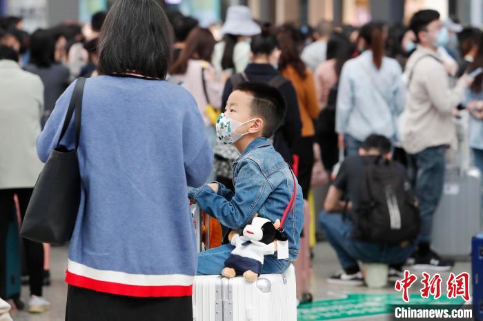 家长与孩子一起戴着口罩等待验票上车. 殷立勤 摄