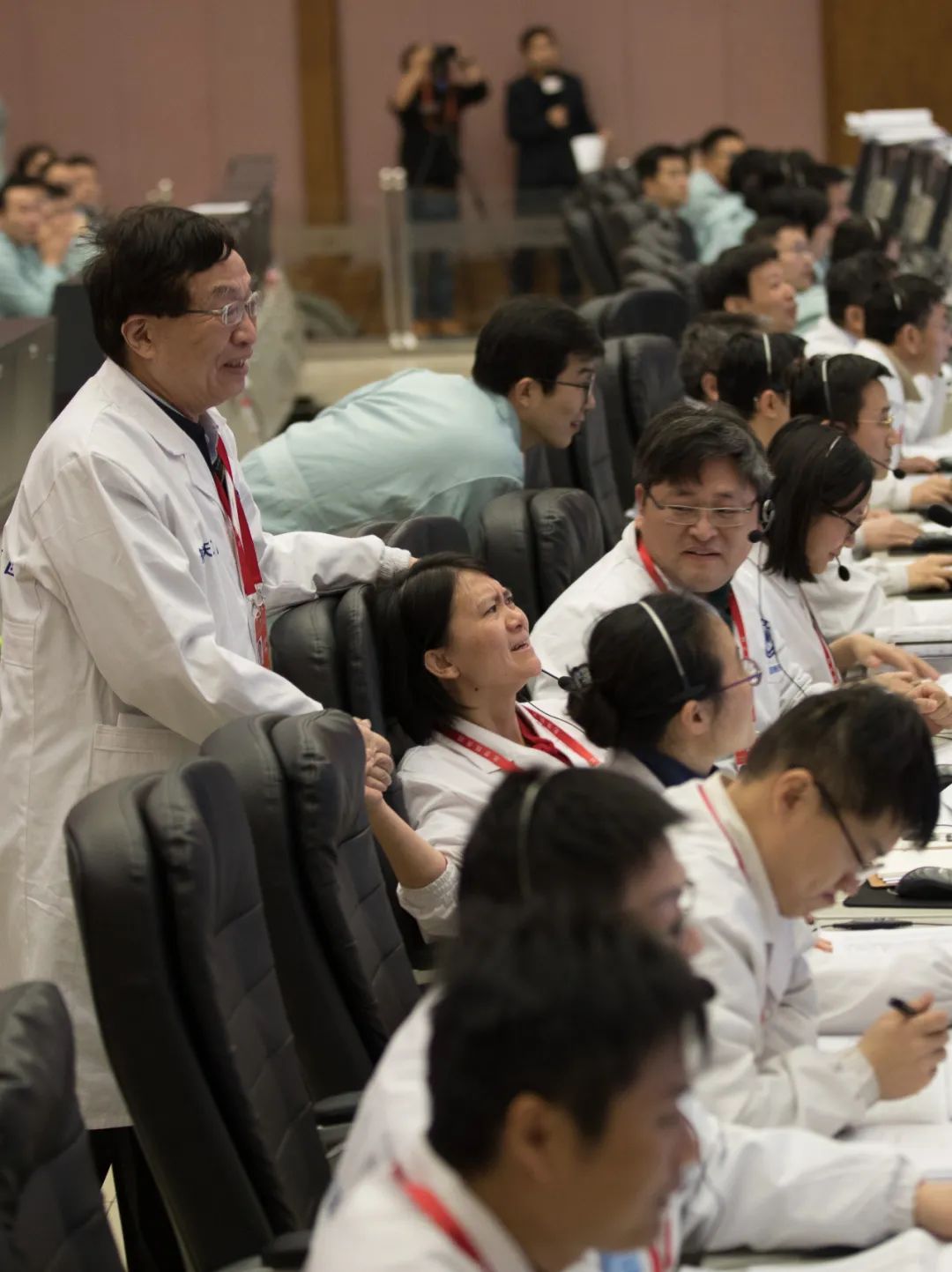 2019年1月3日，在北京航天飞行控制中心，嫦娥四号成功落月的那一刻，74岁的中国航天科技集团五院深空探测和空间科学首席科学家、嫦娥一号卫星总设计师叶培建院士（左一）静静走到嫦娥四号探测器项目执行总监张熇的身后，对她表示祝贺和鼓励。两代“嫦娥人”的手紧紧握在了一起。新华社记者 金立旺 摄
