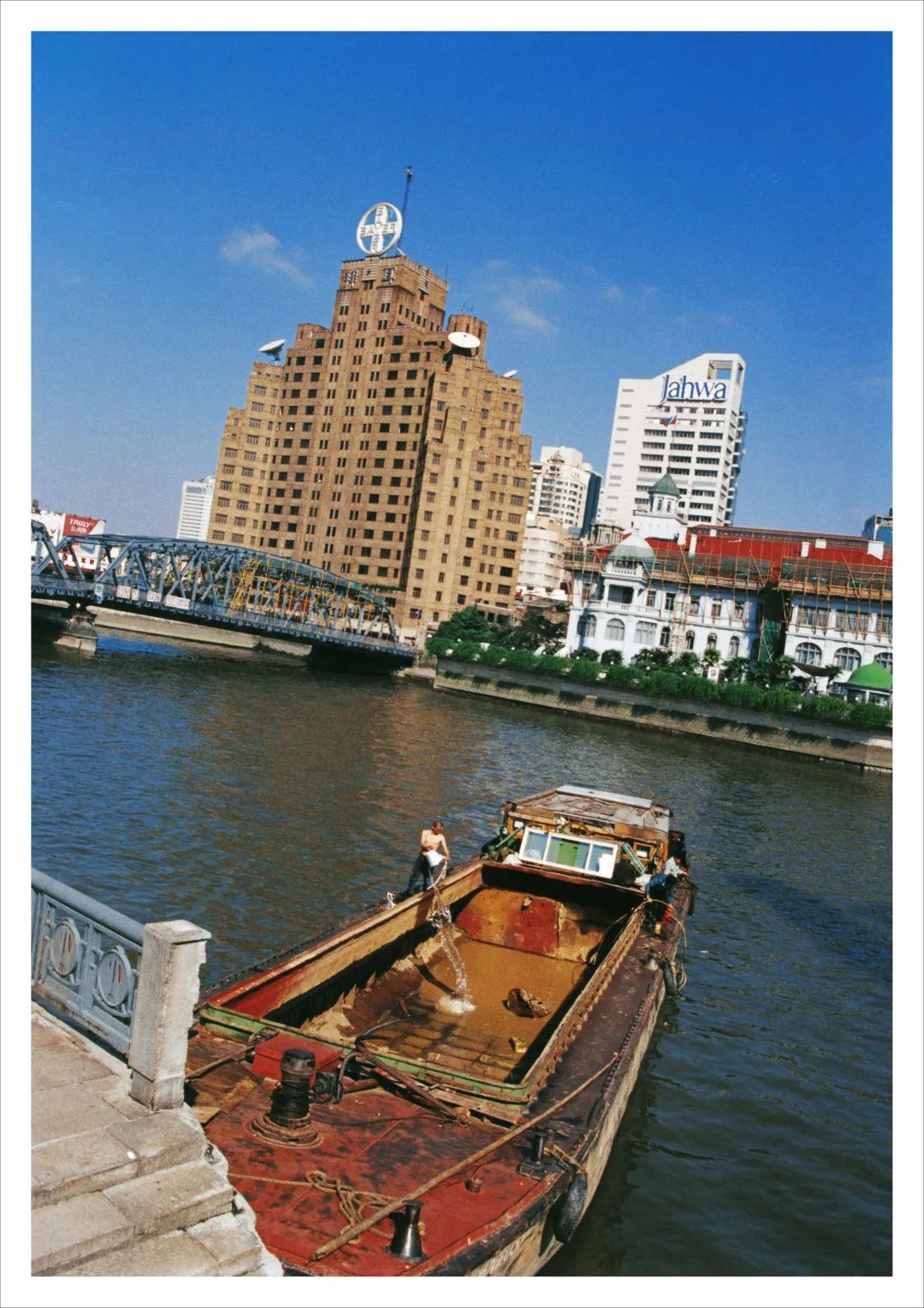 何云昌，《上海水记》 ，2000，行为表演照片，126 × 180 cm。时间：2000年11月3 日，地点:上海 苏州河过程：何云昌在苏州河下游取10吨水运往上游5公里处， 再把10吨水倒回河里——让10吨水重新流淌5公里。&nbsp;