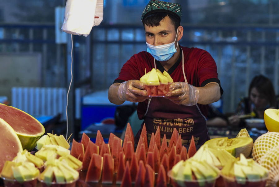 在新疆和田夜市，一商贩展示刚刚切好的瓜果（2020年5月18日摄）。新华社记者 王菲 摄