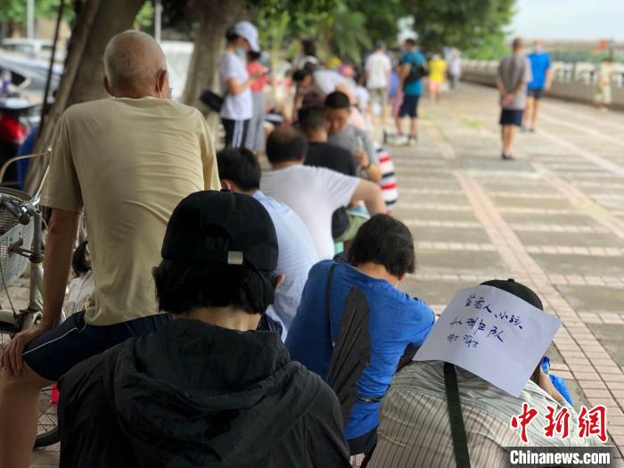 广州南浦岛居民坐在板凳上排队测核酸。孙秋霞 摄