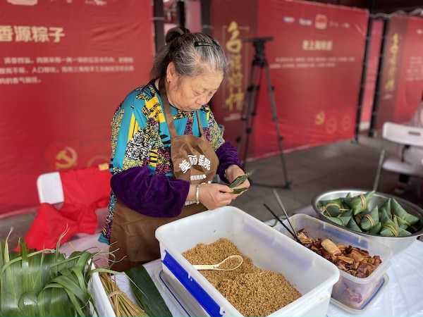 糯香源的老太太正在麻利地演示粽子制作