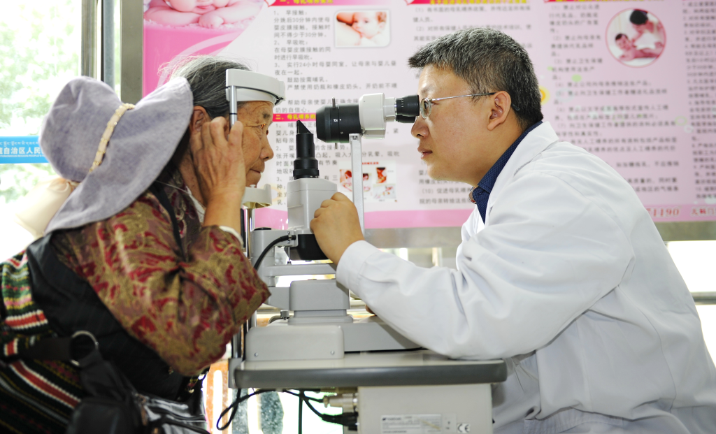 山东省立医院青年志愿者为藏族妇女做眼部检查。（2015年6月23日摄）新华社记者 张汝锋 摄