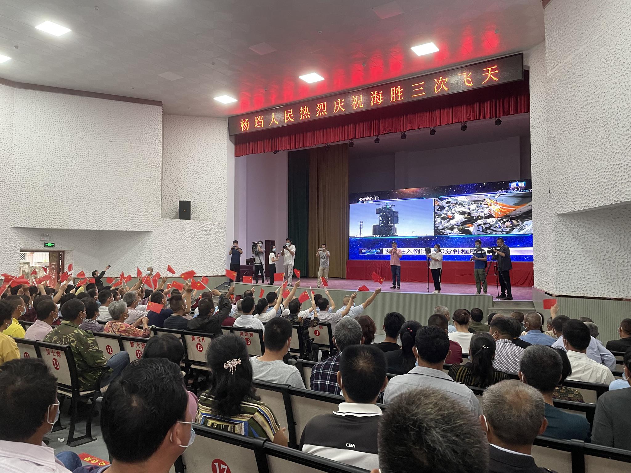 6月17日，杨垱影剧院礼堂聚满了聂海胜家乡的居民，大屏幕正在直播神舟十二号发射过程。新京报记者 周思雅 摄