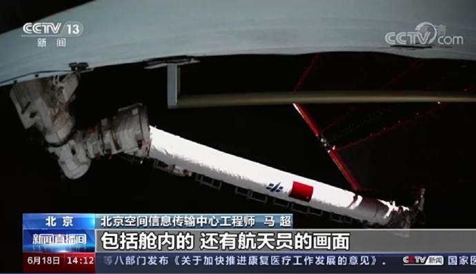 从报道截图可见，空间站的机械臂上有一面五星红旗以及中国载人航天标志。