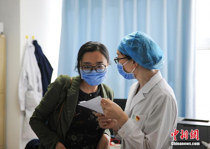 郑宝英正在与同事交接工作 中新网记者 翟璐 摄