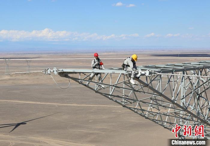国网新疆电力有限公司带电作业人员在塔顶地线支架更换开口销。　张利民 摄