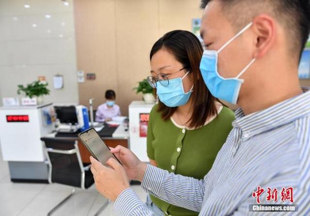 图为6月18日,银行工作人员向市民演示如何查询以“数字人民币”形式领到的工资。 中新社记者 韩冰 摄