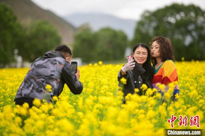 图为游客在油菜花海里拍照留念。贡嘎来松 摄