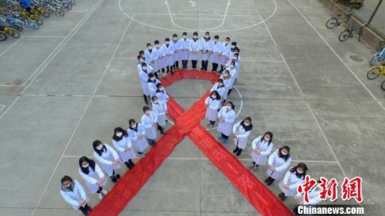 图为大学生们携手“抗艾”，拼大型“红丝带”图案。　孟德龙 摄