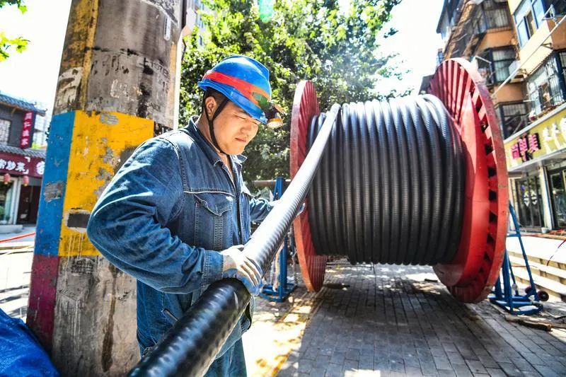 7月13日,电力工作人员进行城市道路架空线缆落地作业.