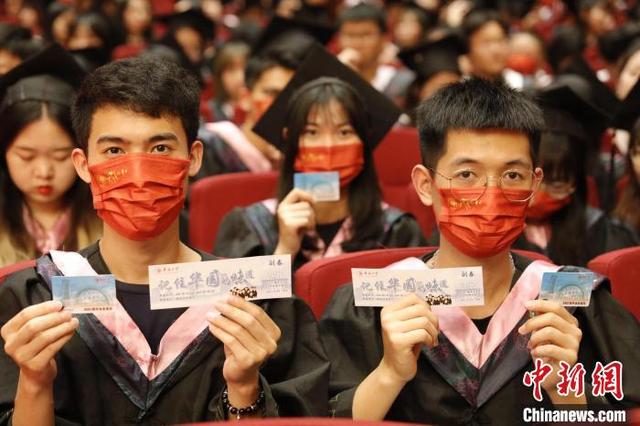 华侨大学毕业生们展示学校提供毕业礼包三件套。 刘沛 摄