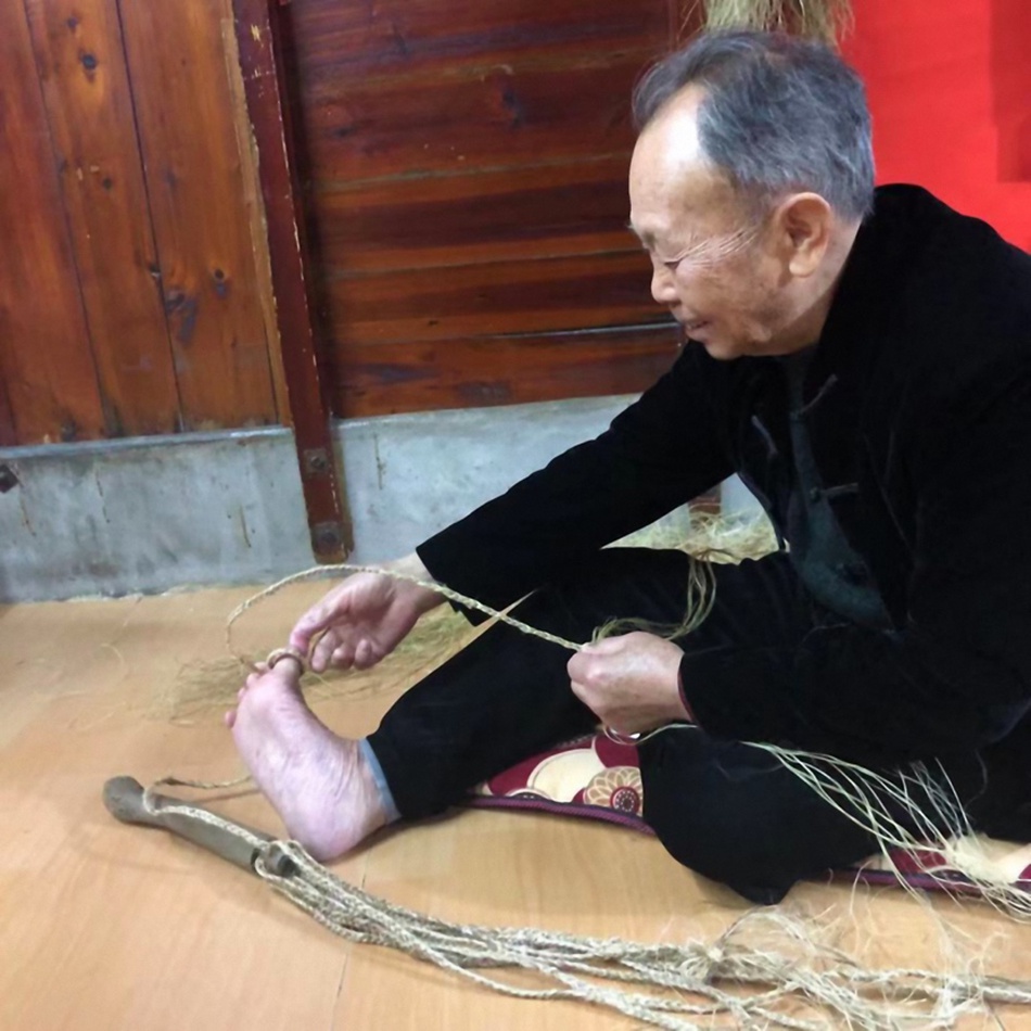 正在编法索的爱食伯，法索是闽越蛇崇拜的重要遗存，为木刻蛇头麻绳身