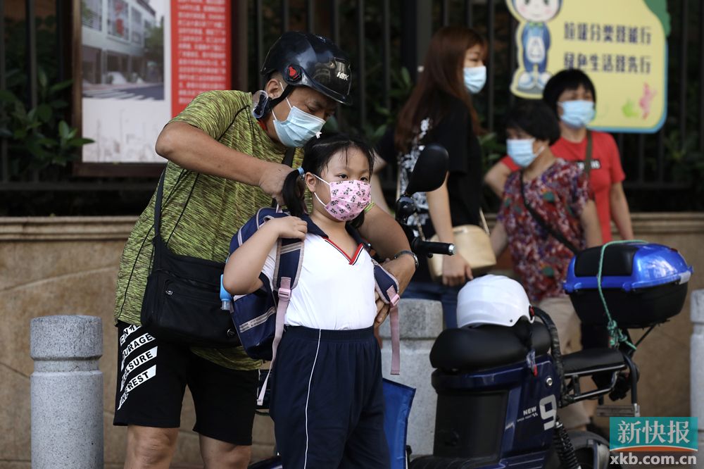 在广州菩提路小学沙园校区,家长正帮学生调整书包.