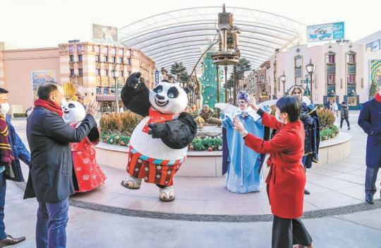 昨天上午9点，在北京环球影城，装扮得富有新年气息的主题IP角色和园区工作人员团队在入口处迎接新年首批游客，与游客合影，并为幸运家庭赠送礼物。本报记者 武亦彬摄