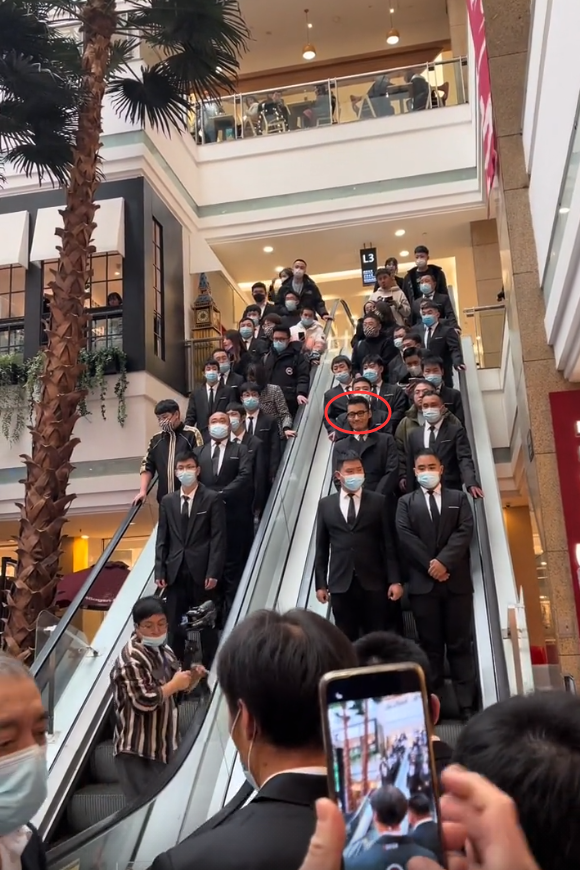 胡兵从二楼下电梯进入活动现场,身边站满了保镖,电梯下面也有一排保镖