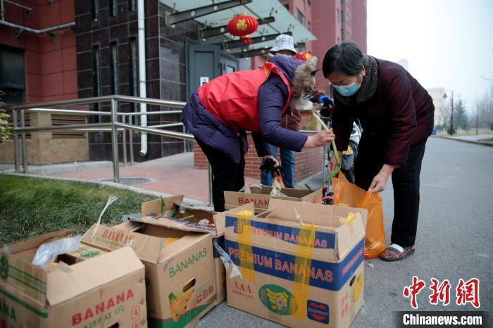 1月5日，陕西西安，北郊一小区居民在单元楼下领取免费蔬菜。张远 摄