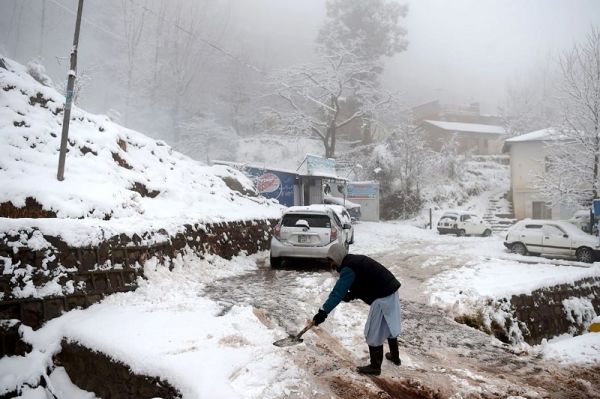1月8日，一名男子在巴基斯坦北部度假胜地穆里山区的雪灾现场清扫路面。