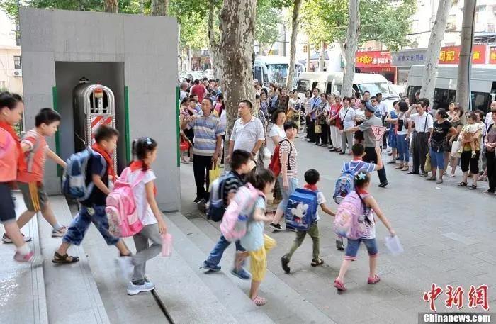 资料图:武汉一小学门外等待学生放学的家长们。中新社发 张畅 摄