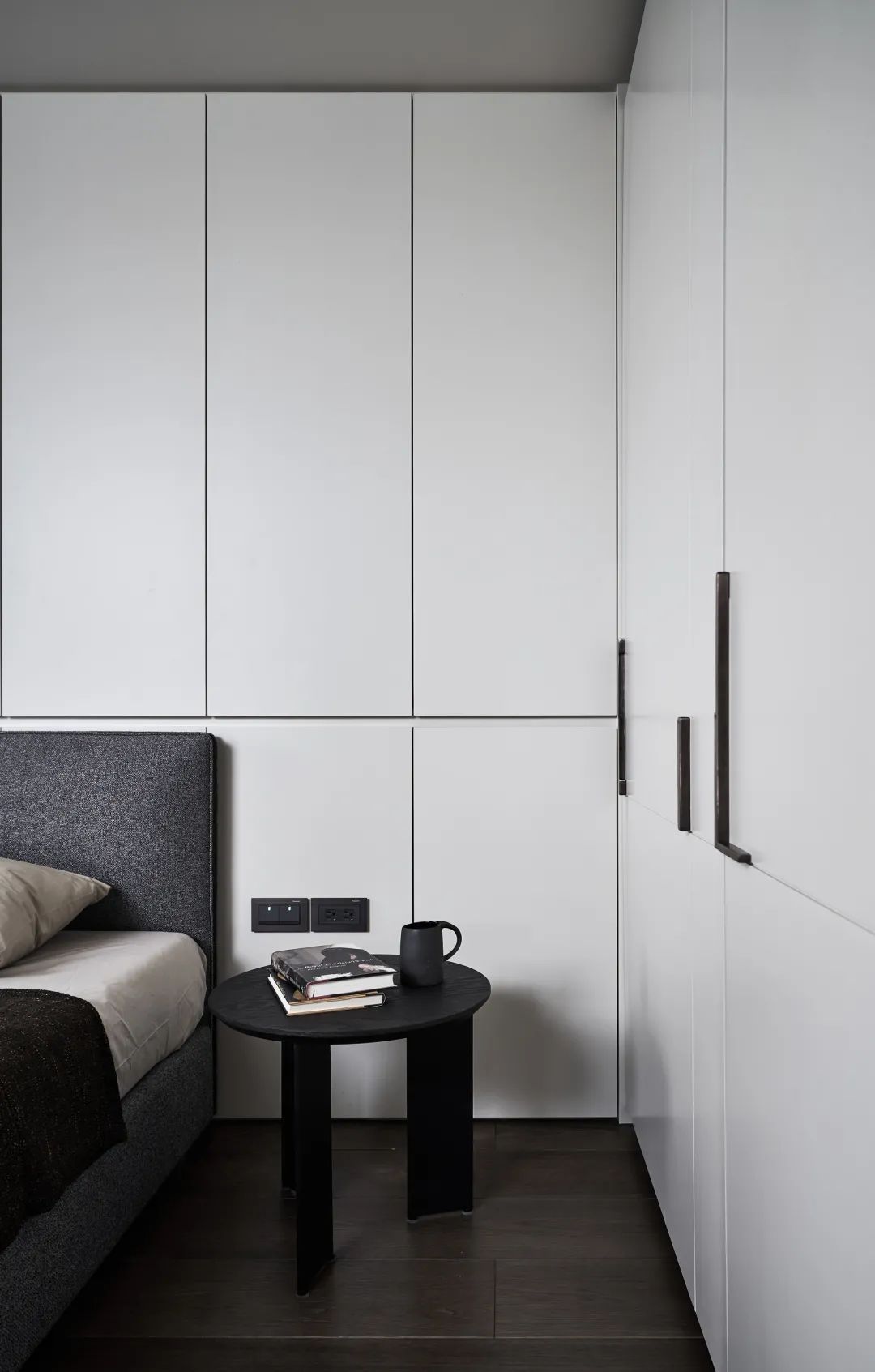 次卧的墙面与衣柜都是采取简约现代的白色材质,布置上灰色布艺床