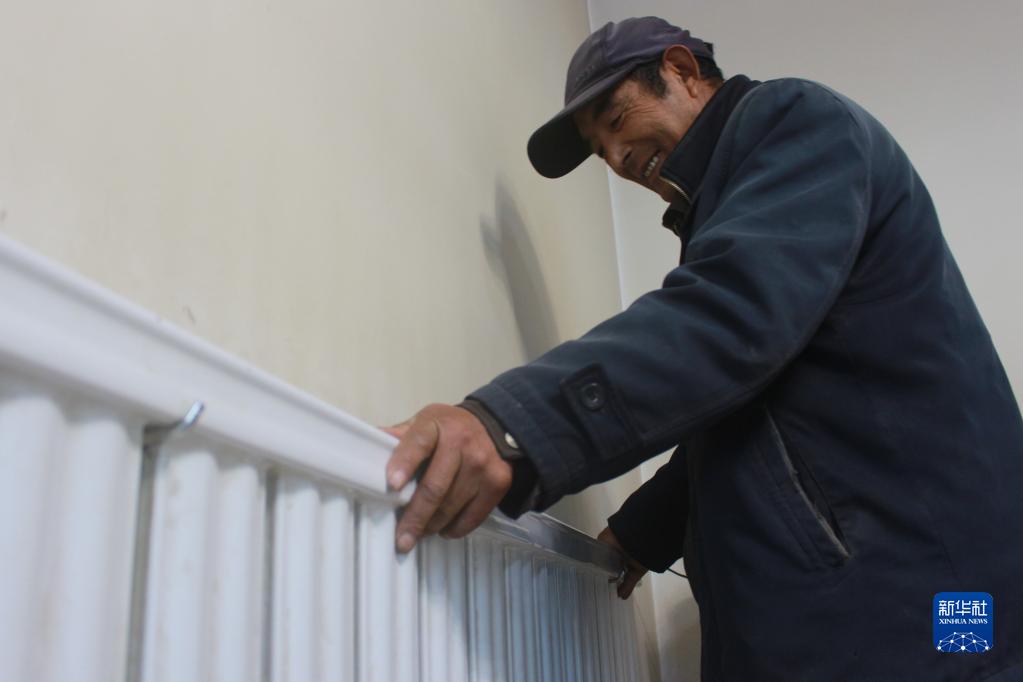 　　2020年12月1日，青海省西宁市湟源县申中乡前沟村村民王录在感受新装暖气片的温度。新华社记者 解统强 摄