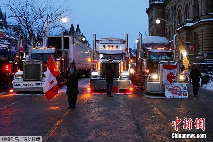 当地时间2月4日，加拿大首都渥太华国会山附近，参与卡车司机示威的人员站在车队旁。