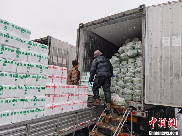 2022年2月13日，新发地市场商户们冒着大雪搬运蔬菜。 北京市商务局供图