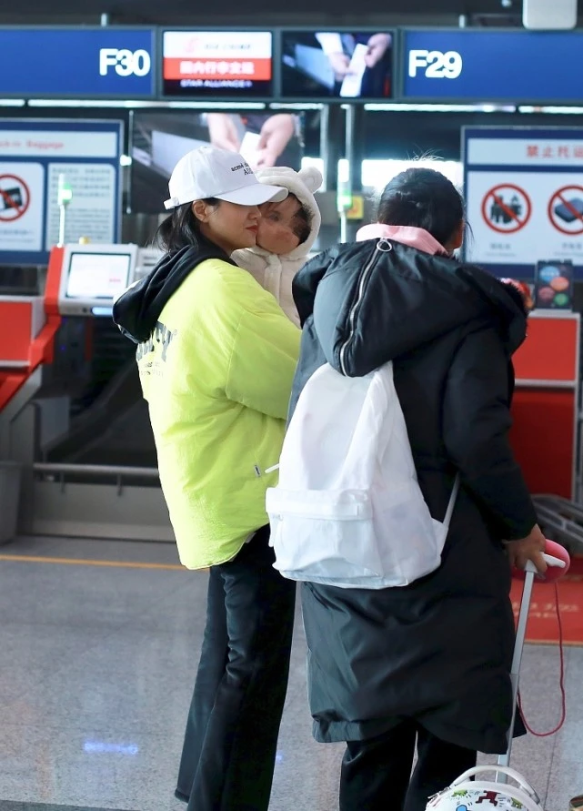 朱丹罕见抱女儿走机场白帽黄衣超扮嫩成功哪像四十岁的女人