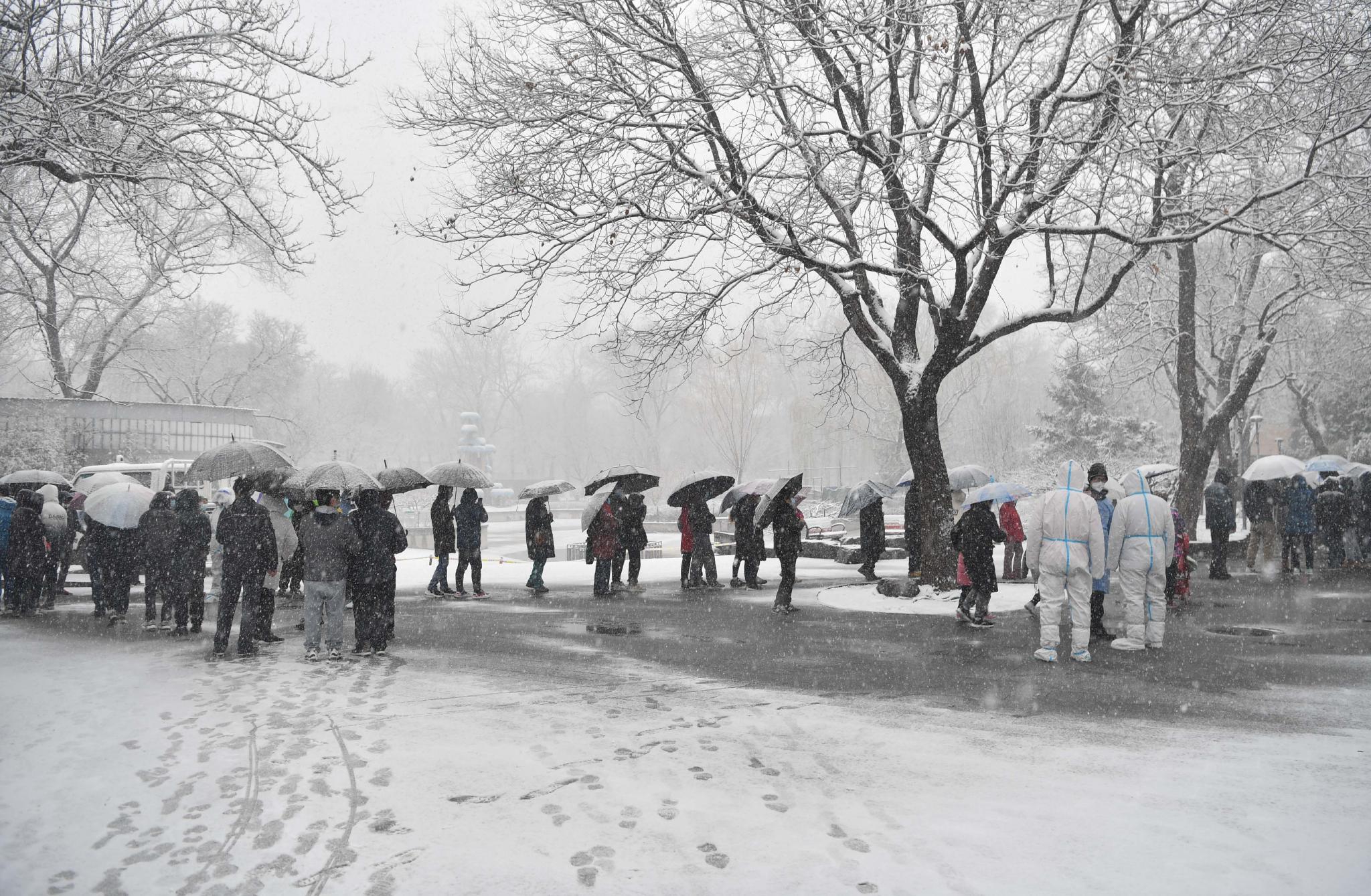 3月18日,南馆公园,北新桥街道居民在大雪中排队等待进行核酸检测.