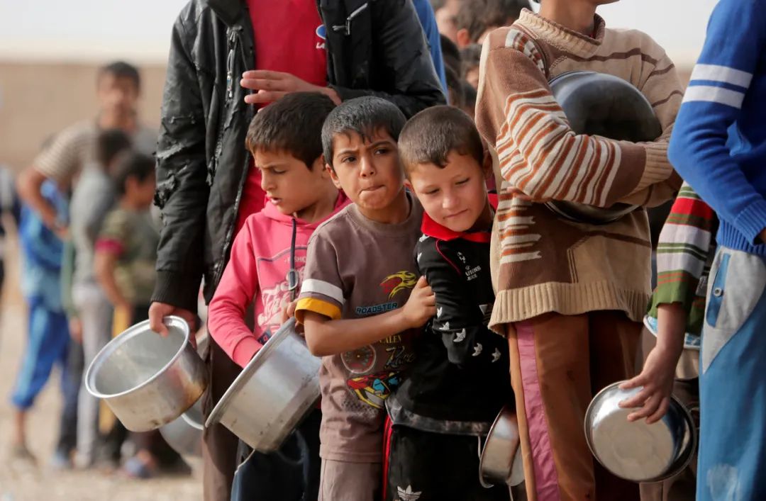 △伊拉克摩苏尔一所难民营里，无家可归的民众排队领取食物。