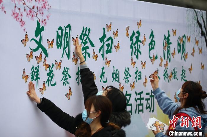 资料图：民众在“文明祭扫 绿色清明”背景板上贴上“蝴蝶”，表明自身将响应倡议。　泱波 摄