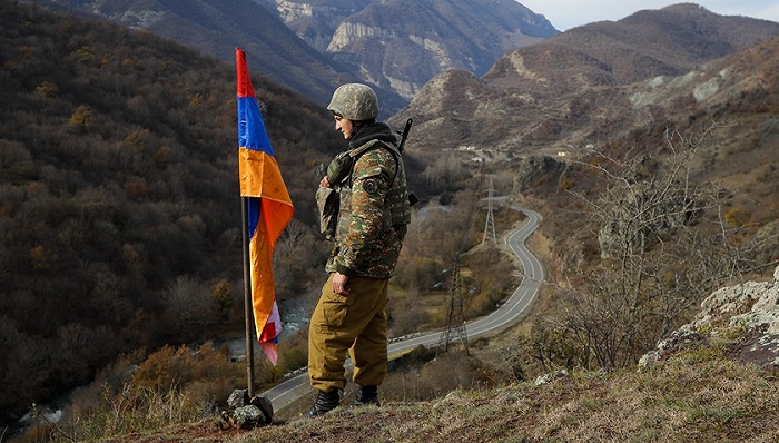 2020年11月25日，纳卡地区，一名亚美尼亚士兵站在纳戈尔诺-卡拉巴赫的旗帜旁。图片来源：视觉中国