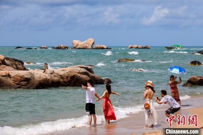 资料图:游客在天涯海角的海边沙滩“拥抱大海”。 范勇 摄