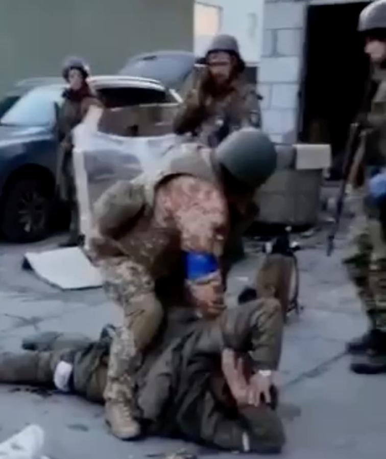 《图片报》图说：一名疑似乌克兰士兵虐待一名俄罗斯战俘，其他三人则在一旁看着，其中一名（中）手臂上可能戴着“亚速团”的徽章