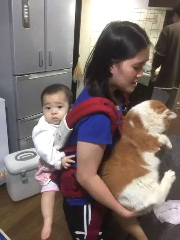 主人前面抱着小猫咪后面背着小宝宝，小宝宝满脸委屈休闲区蓝鸢梦想 - Www.slyday.coM