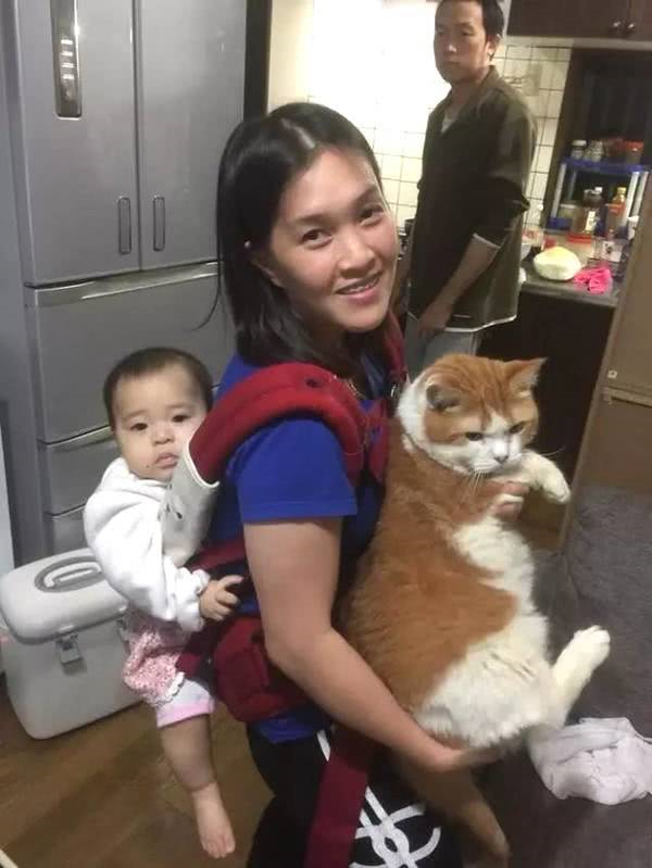 主人前面抱着小猫咪后面背着小宝宝，小宝宝满脸委屈休闲区蓝鸢梦想 - Www.slyday.coM
