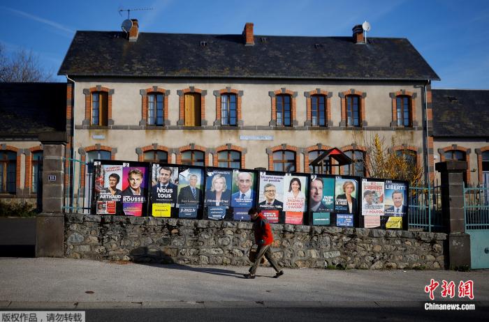 当地时间4月10日，法国街头，行人从2022年法国总统大选候选人广告牌前走过。
