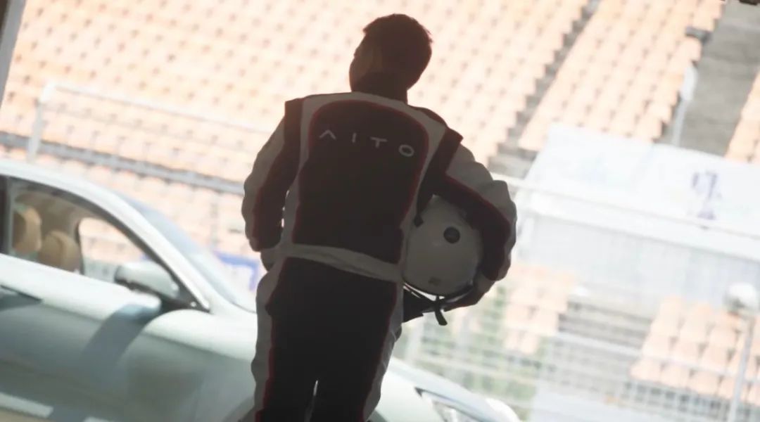 配图是余承东身着赛车服,手抱头盔的背影,朝着远处一辆车走去,车的