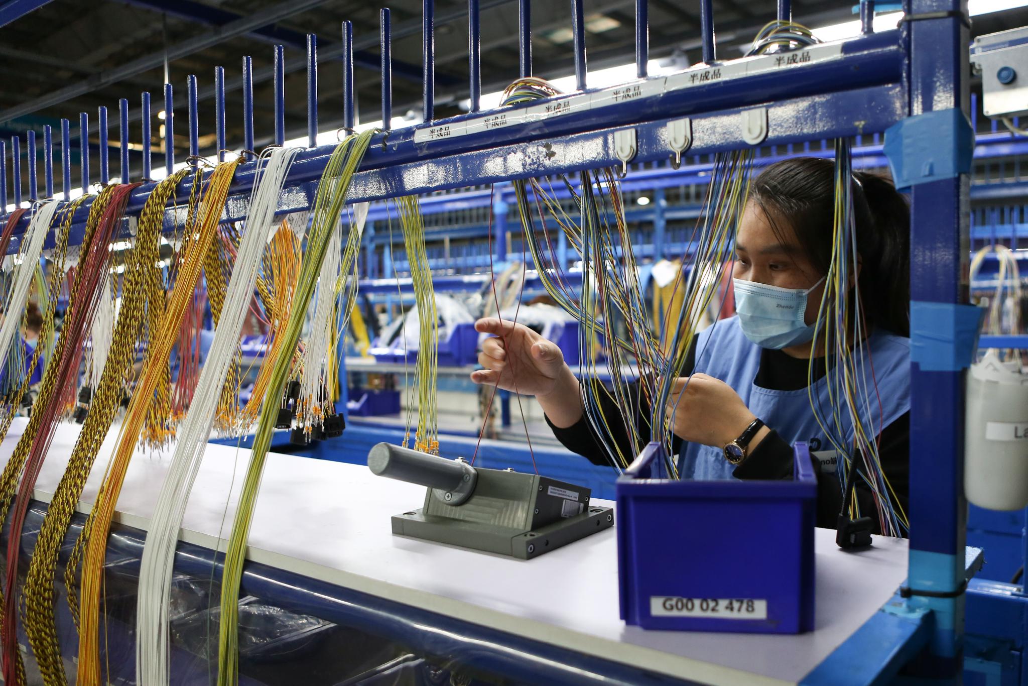 德科斯米尔(鞍山)线束系统有限公司的工人在车间内生产汽车线束