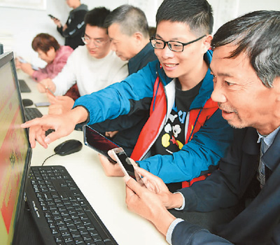 江苏大学志愿者在帮助老年人学习网上购物技能。石玉成摄