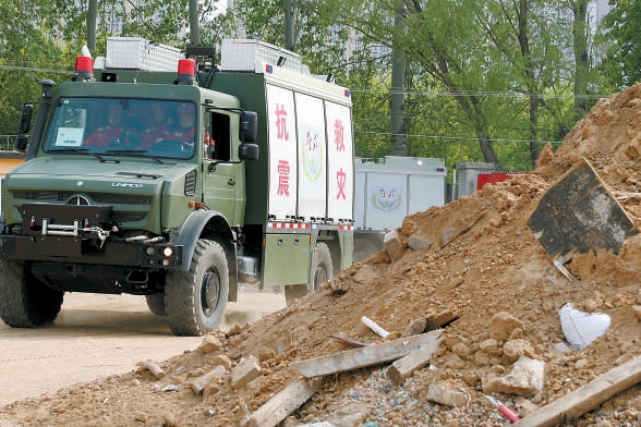 一辆救援指挥车带领着三辆地震救援车拉响警报,直奔救援现场.