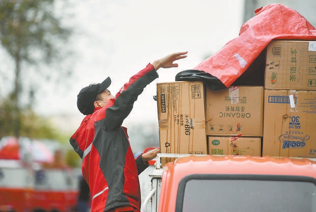 蒙蒙细雨,在通州一快递网点,快递员用苫布将货物覆盖好,准备出发送货