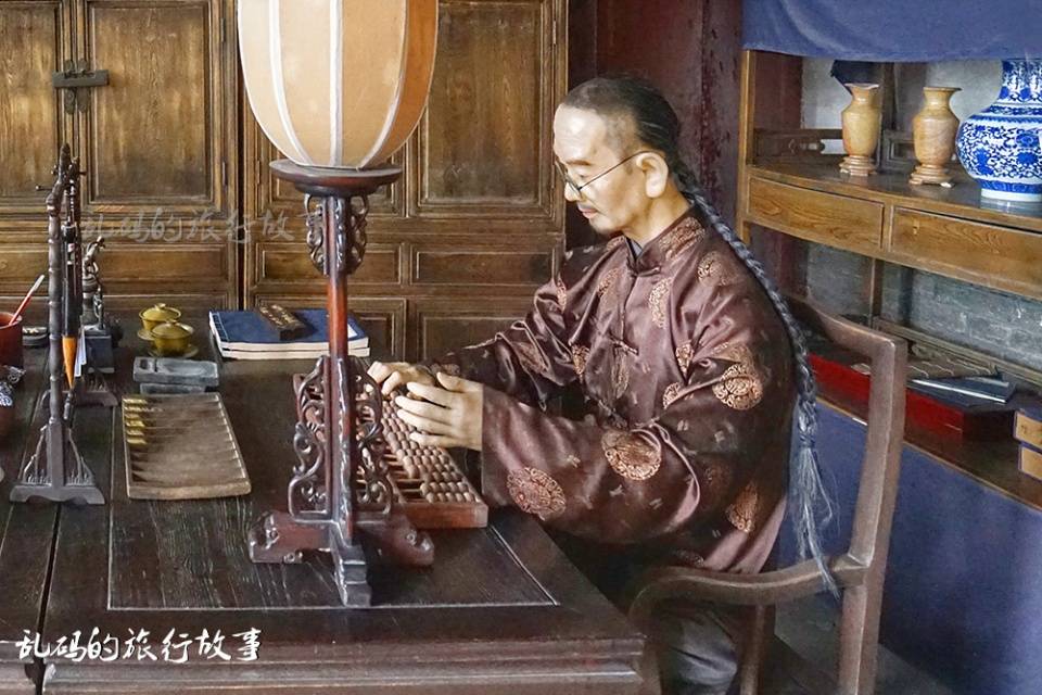 在帐房的左侧,还有一位正在用算盘算账的账房先生雕塑.