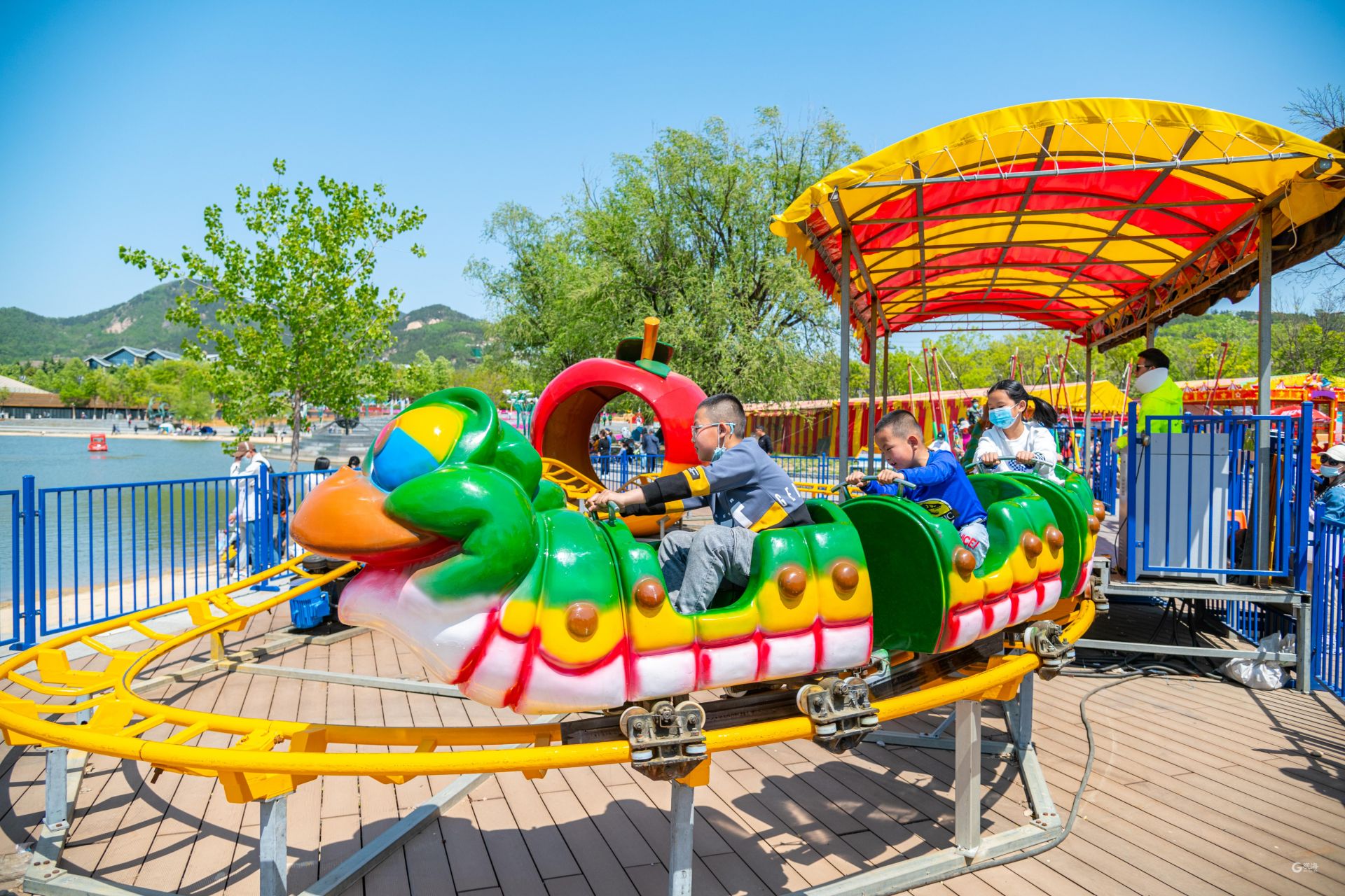 在儿童游乐区,市民排队体验滑道和摩天轮.