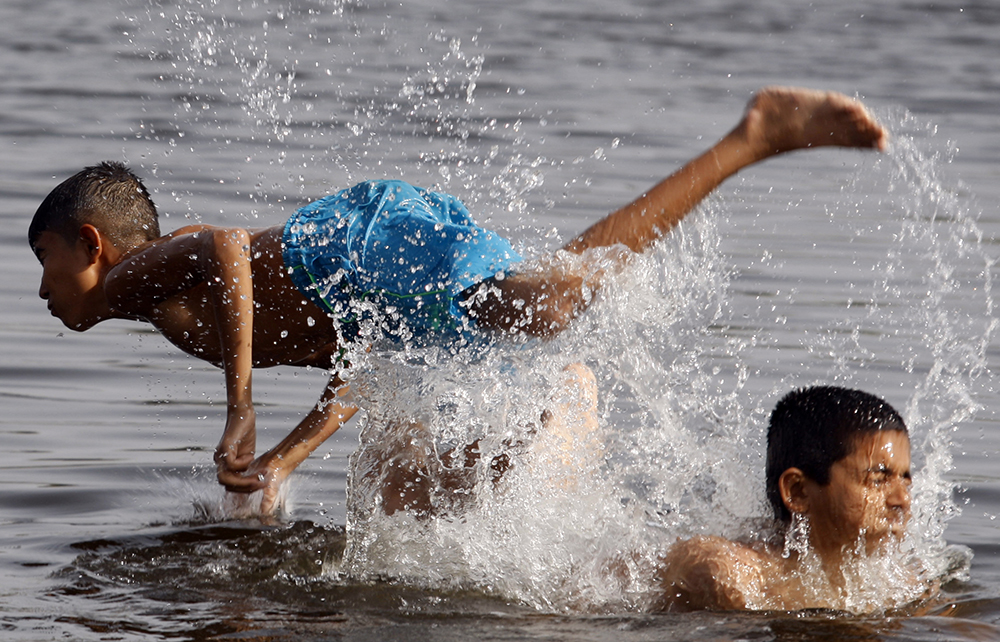 当地时间2022年5月1日,巴基斯坦拉合尔,男孩们在小溪中戏水消暑.