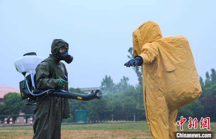 图为演练中身穿绿色防化服的官兵对身穿黄色重型防化服的"染毒人员"