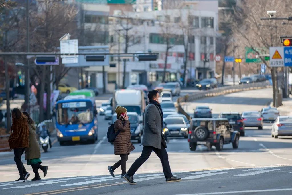 资料图：行人佩戴口罩在韩国首尔过马路。新华社记者 王益亮 摄
